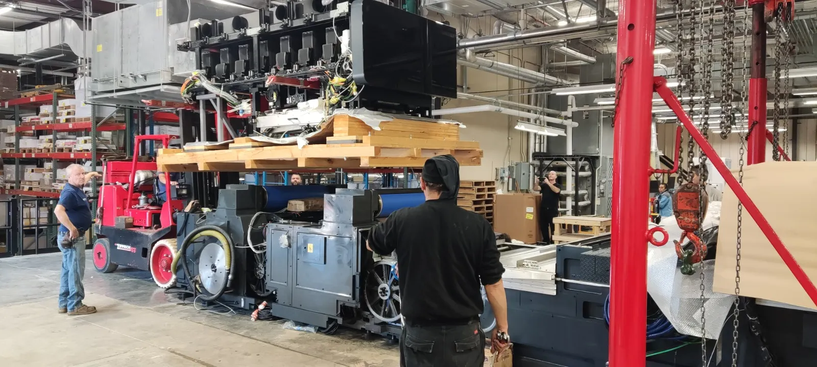 צוות מכין מכונת דפוס כבדה בתוך מפעל לקראת אריזה ושינוע