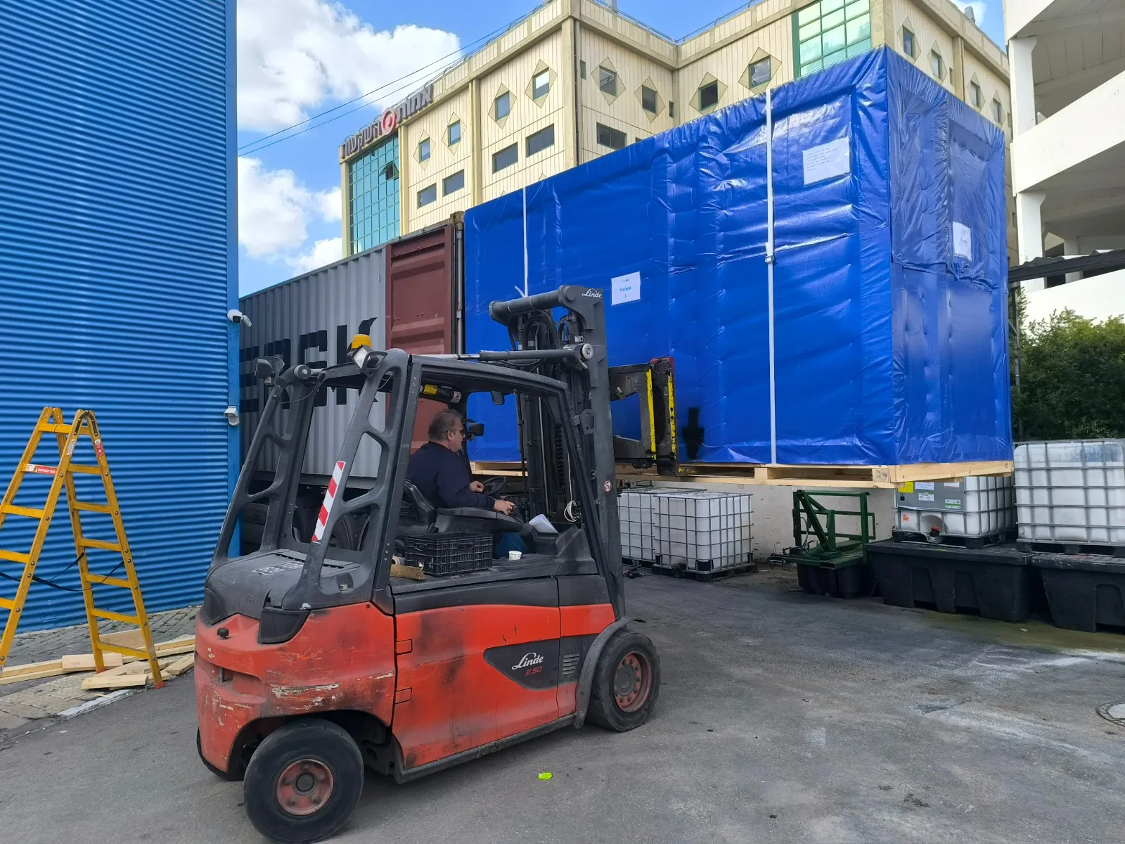 ציוד תעשייתי עטוף ביריעת פוליאתילן כחולה על גבי מלגזה