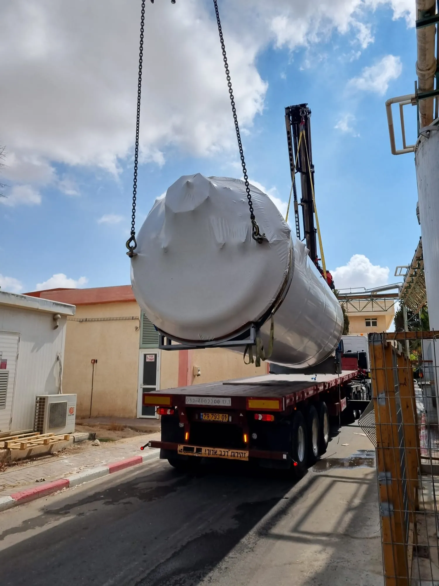 טכנאי עובד על חיבור צינור תעשייתי מעל מכל מתכת